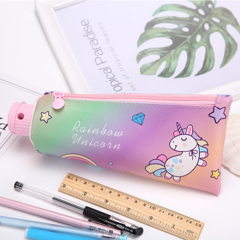Toothpaste Pencil case with rainbow unicorn design on a white surface with stationery items.