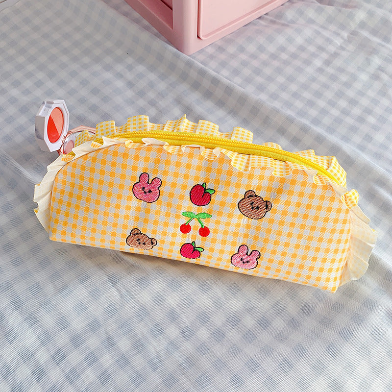 Yellow checkered pencil case with cartoon designs on a checkered surface