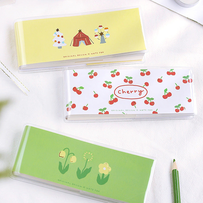 Three small notebooks with different designs on a white surface with a patterned plastic cover.