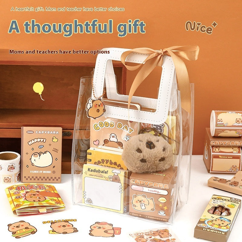 Capybara Gift set with cartoon-themed items including a plush toy, stationery, and a bag on a white surface.