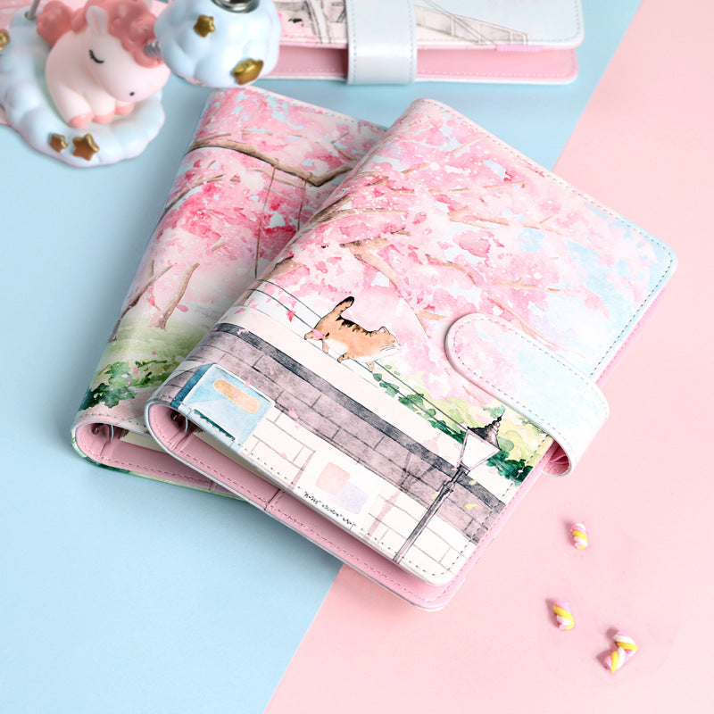 Pink planner with cherry blossom design on a pink and blue background