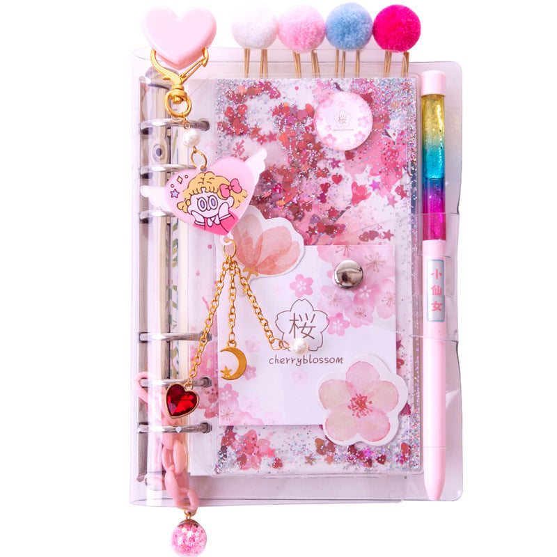 Decorative planner with cherry blossom design, charms, and a pen on a white background