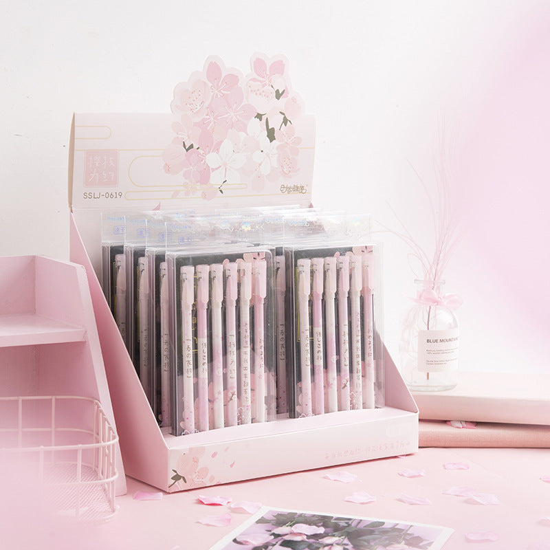 Display of pink and gray pens in a decorative box with floral design on a pink background.