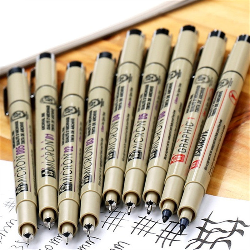Set of Micron and Graphic pens on a wooden surface with a white background