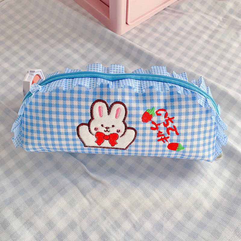 Blue checkered pencil case with a embroidered bunny design on a checkered surface