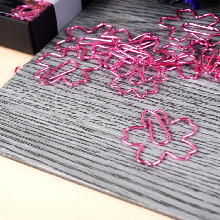 Pink paper clips shaped like flowers on a textured surface