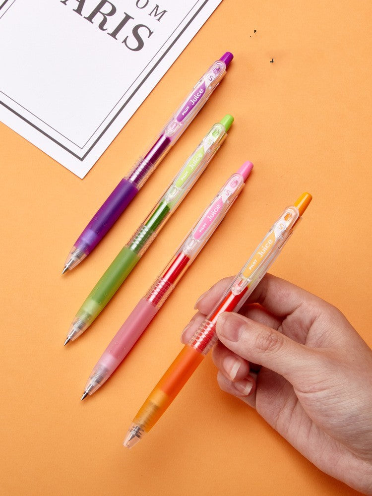 Set of 4 colorful pens on an orange background with a hand holding one pen.