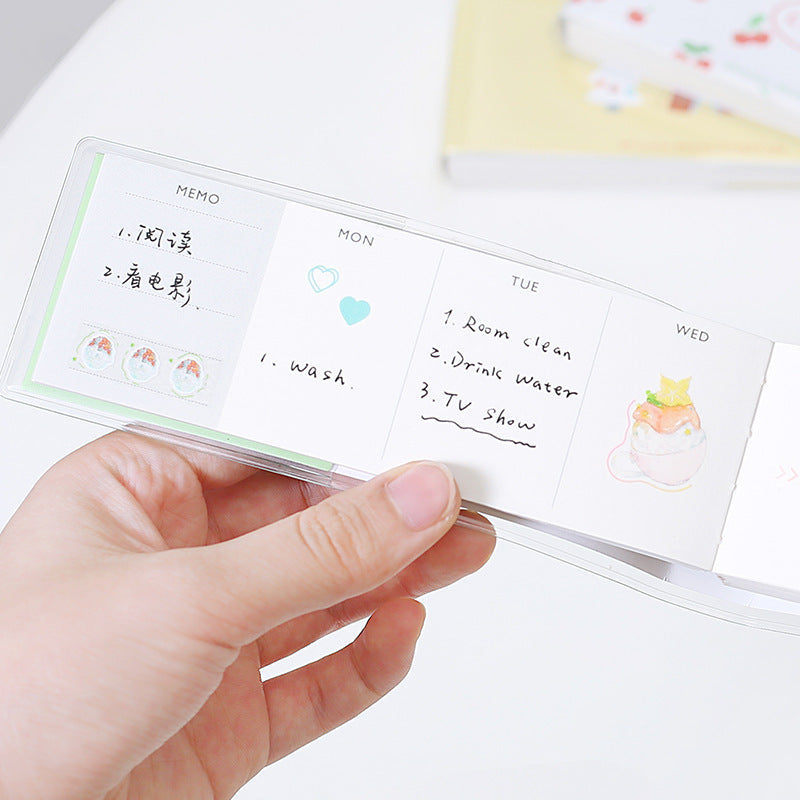 Hand holding a transparent planner with sticky notes and small illustrations.