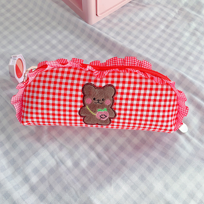 Red and white checkered pencil case with a teddy bear patch on a checkered background