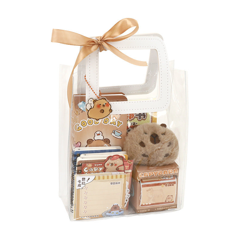 Set of Capybara stationery items including a small plush toy, notepads, and stickers in a clear gift bag with a gold ribbon.