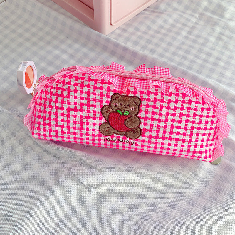 Pink checkered pencil case with a teddy bear design on a checkered surface